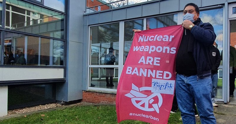 Vor dem Innenhof der Jugendherberge Horn posiert einer der Seeleute aus dem Pazifik mit einem Banner gegen Atomwaffen.