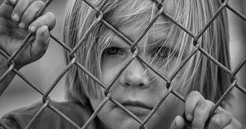 Ein Junge schaut durch einen Drahtzaun - Copyright: © Creative Commons, CC0