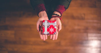 Zwei Hände halten ein Weihnachtsgeschenk - Copyright: Ben White / Unsplash